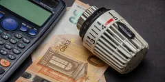 Heizlastberechnung: Nahaufnahme eines Heizkörperthermostats auf einem 50-Euro-Schein neben einem Taschenrechner 