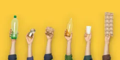PPWR: Sechs erhobene Hände halten vor gelbem Hintergrund verschiedene Verpackungen: eine Plastikflasche, eine Konservendose, zerknülltes Papier, eine Glasflasche, einen Kunststoffbecher und eine Eierverpackung.